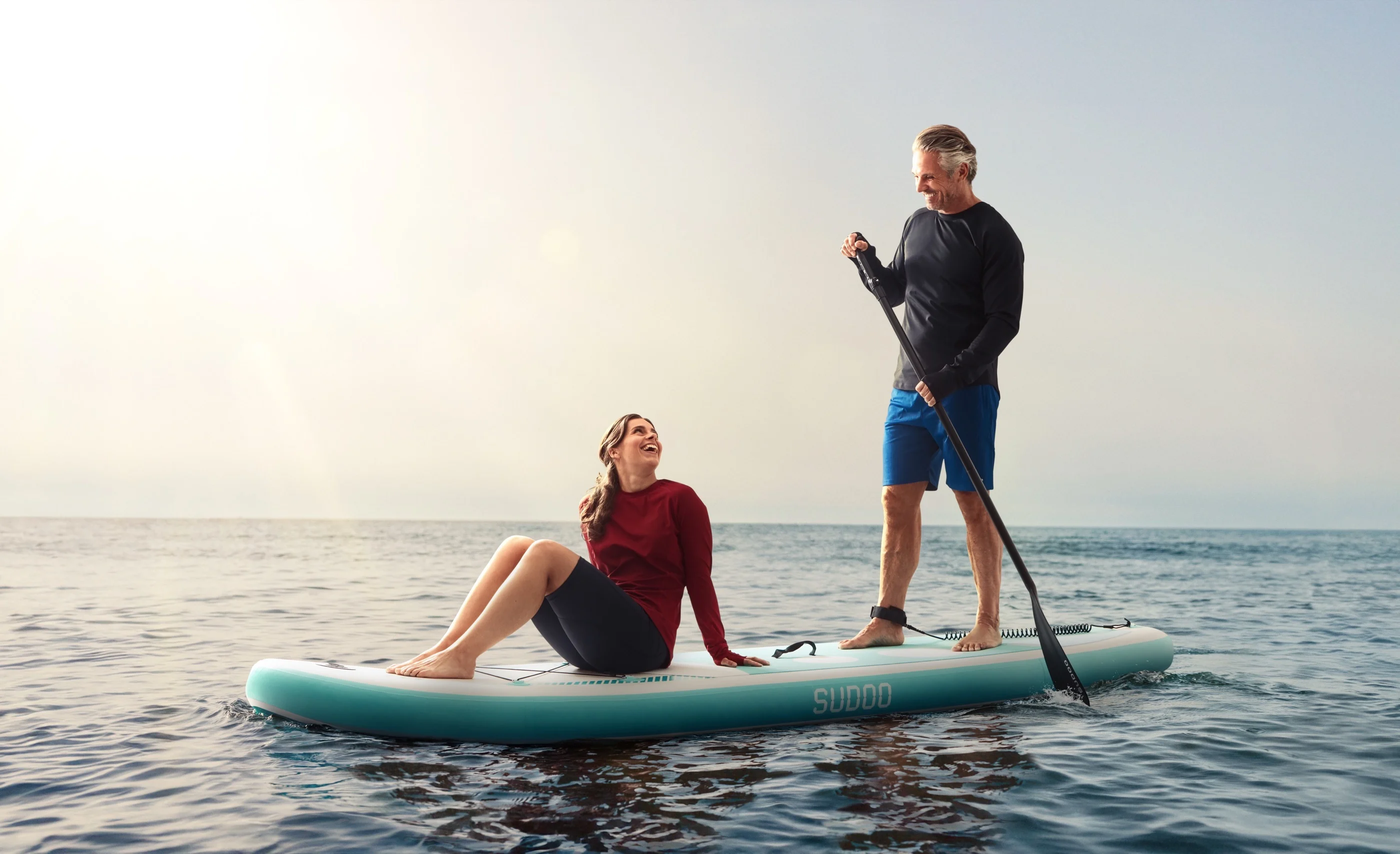 Zwei Menschen auf einem SUP-Board in langärmeliger UVEEKAI-Kleidung